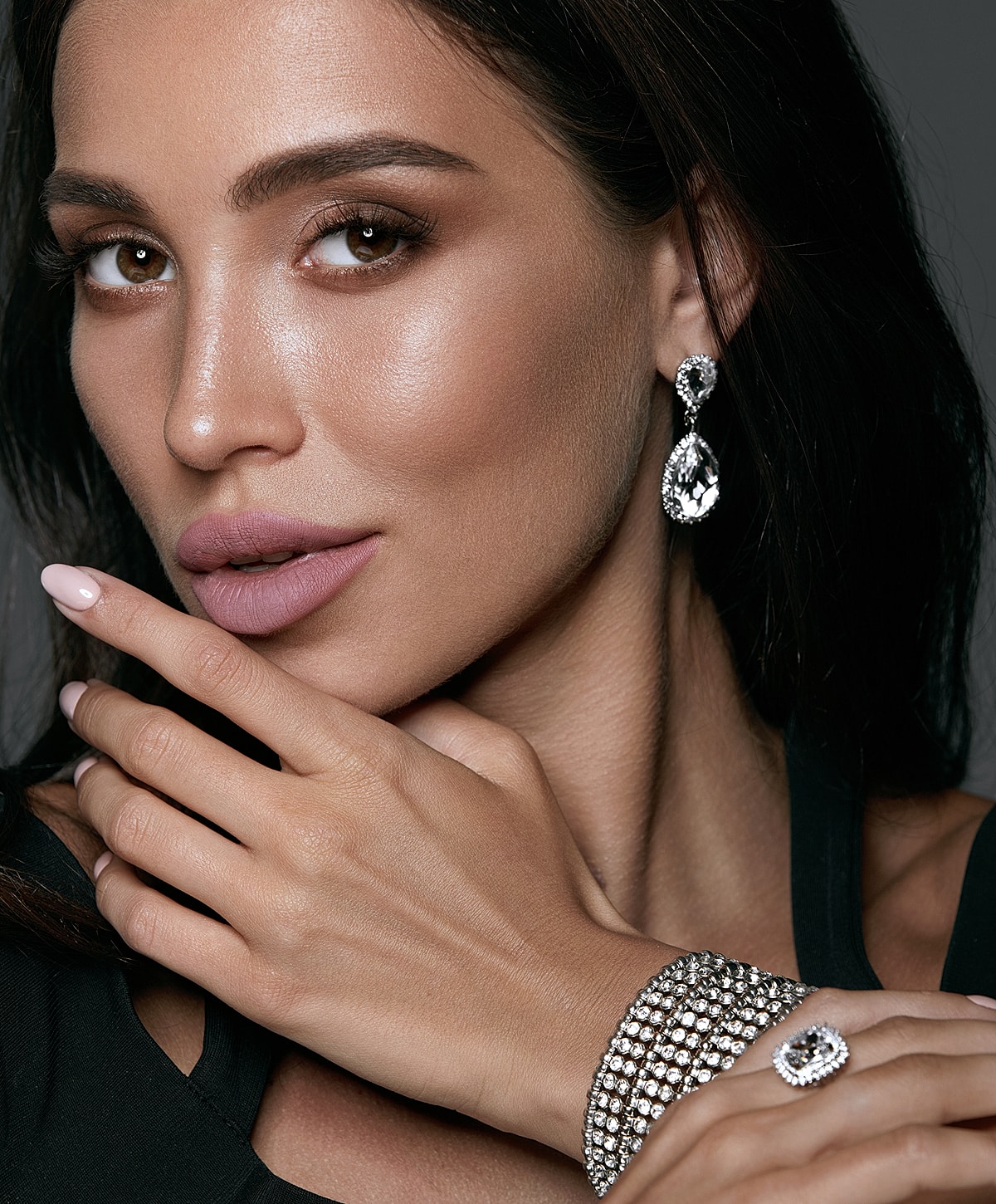 Woman showcasing jewelry and stylish makeup.
