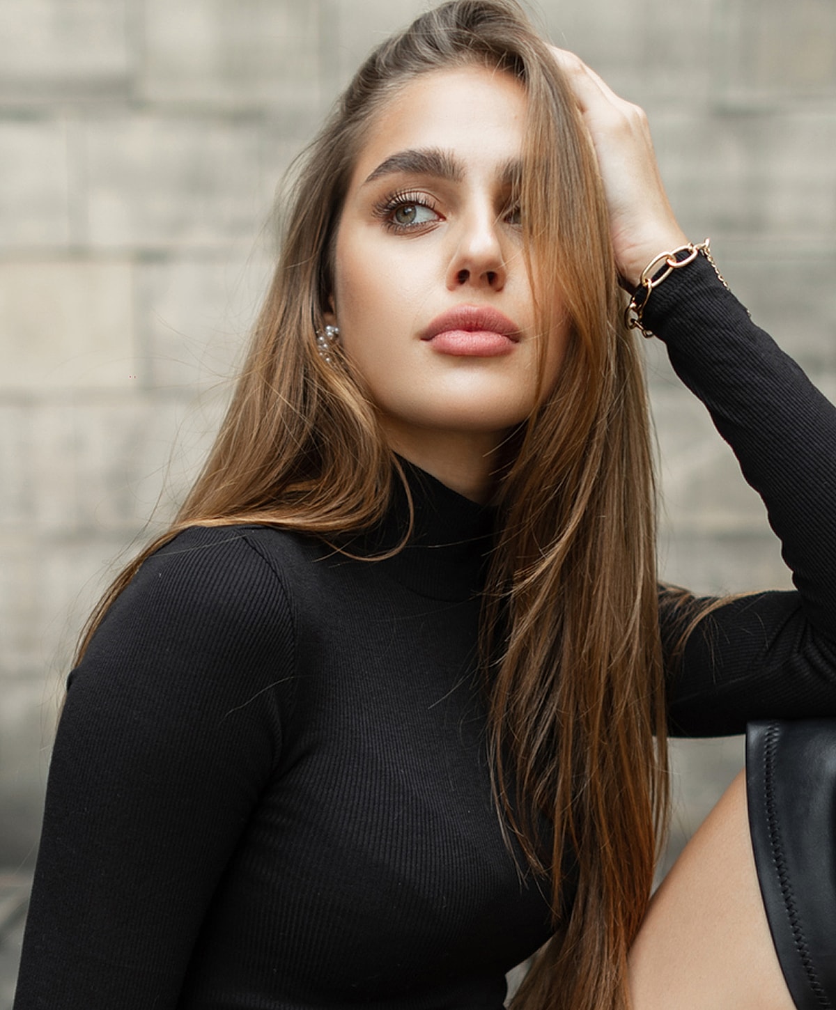 Woman in black turtleneck looking thoughtfully to side.